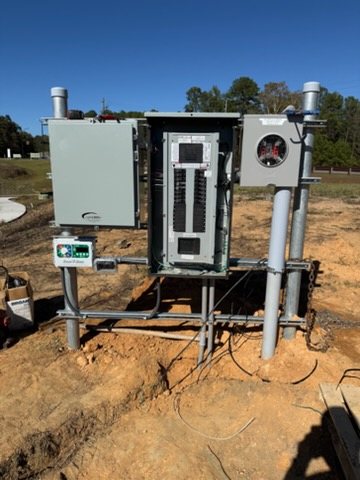 Second angle of the same outdoor service pedestal, showing the meter base, panelboard, enclosure, irrigation controller, and rigid conduit risers.